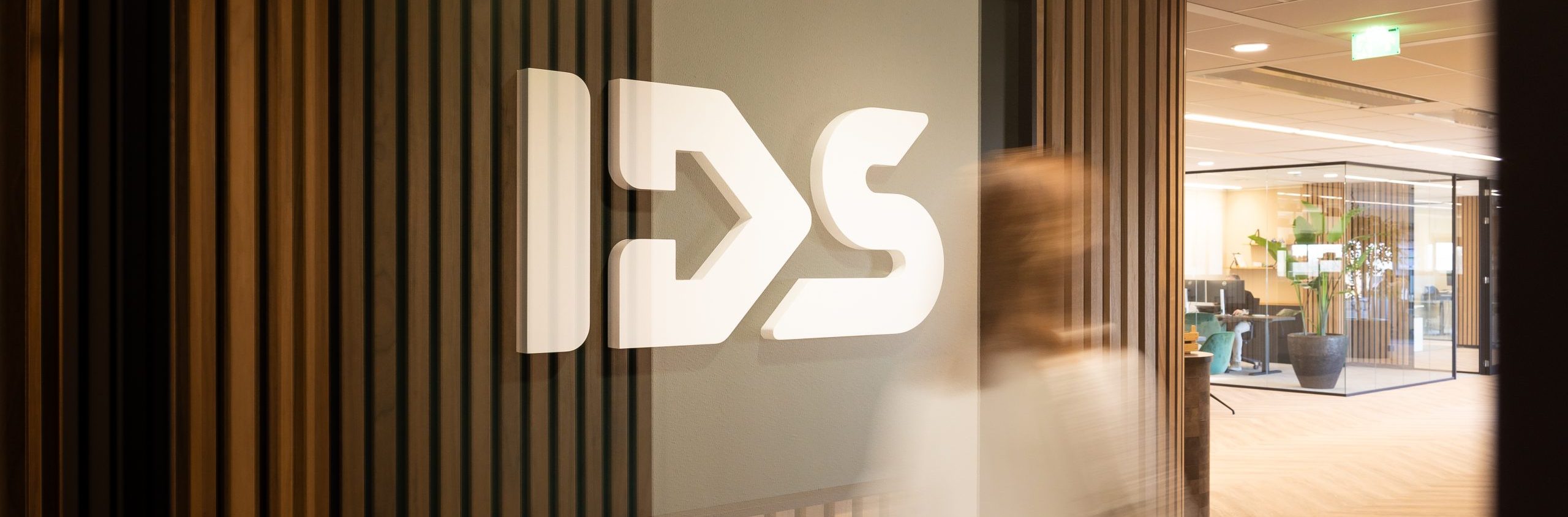 An overview photo of the IDS logo, someone is walking in front of it, making the person look blurred